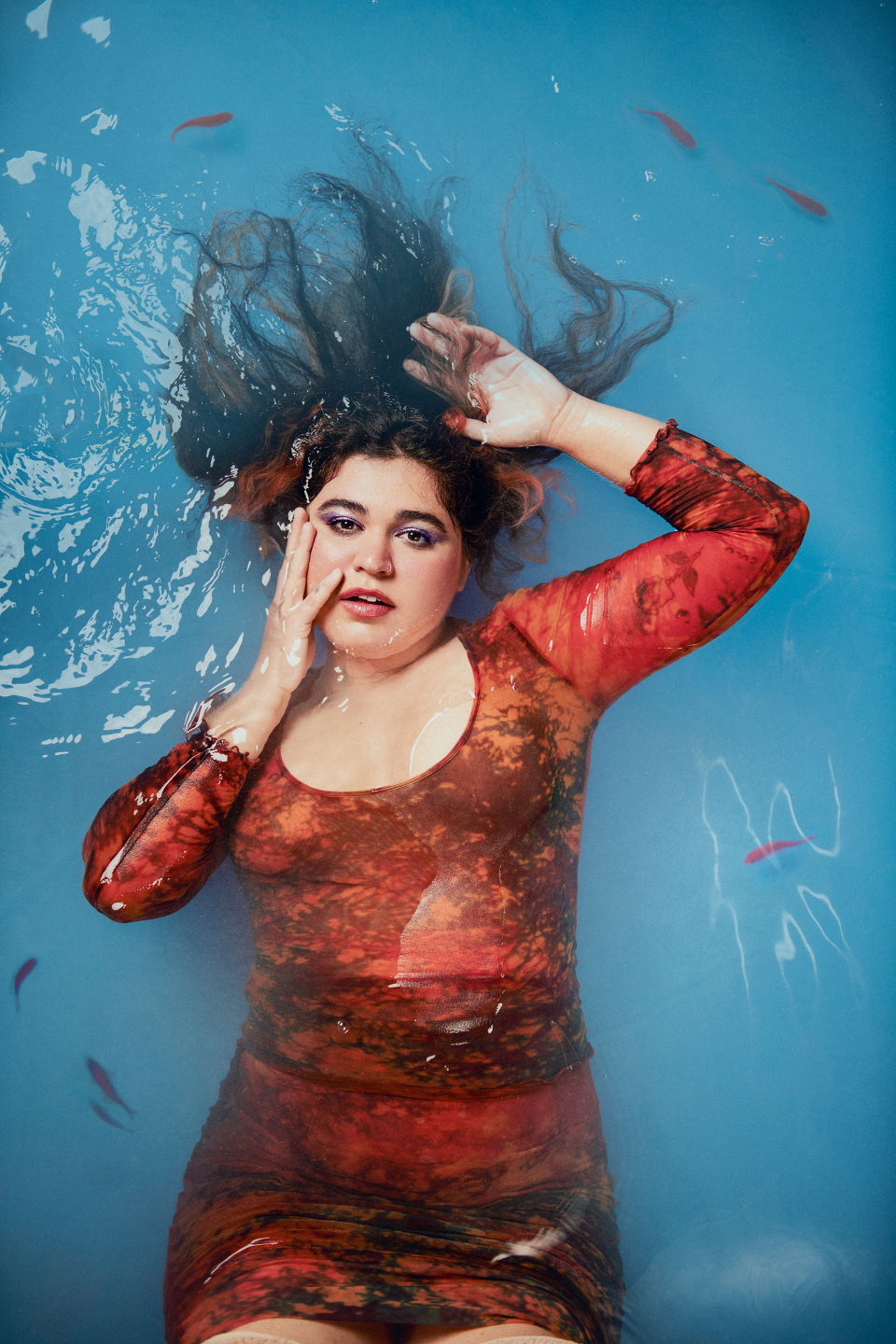 Woman lays in pool with fish