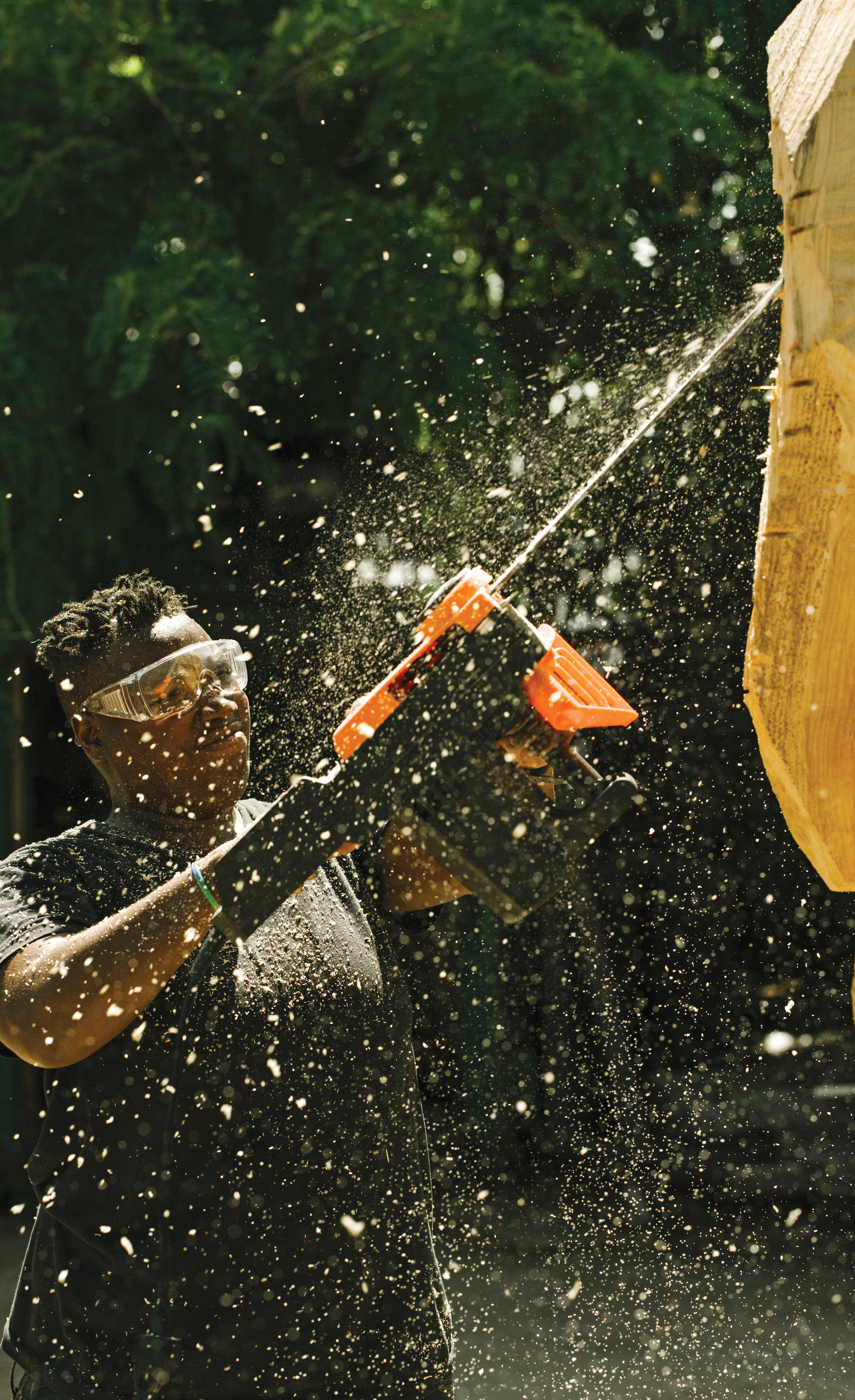 Babirye takes a chainsaw to a tree stump at Socrates Sculpture Park. Born and raised in Uganda, Babirye started carving masks as a way of addressing the violent homophobia she and her friends faced there.