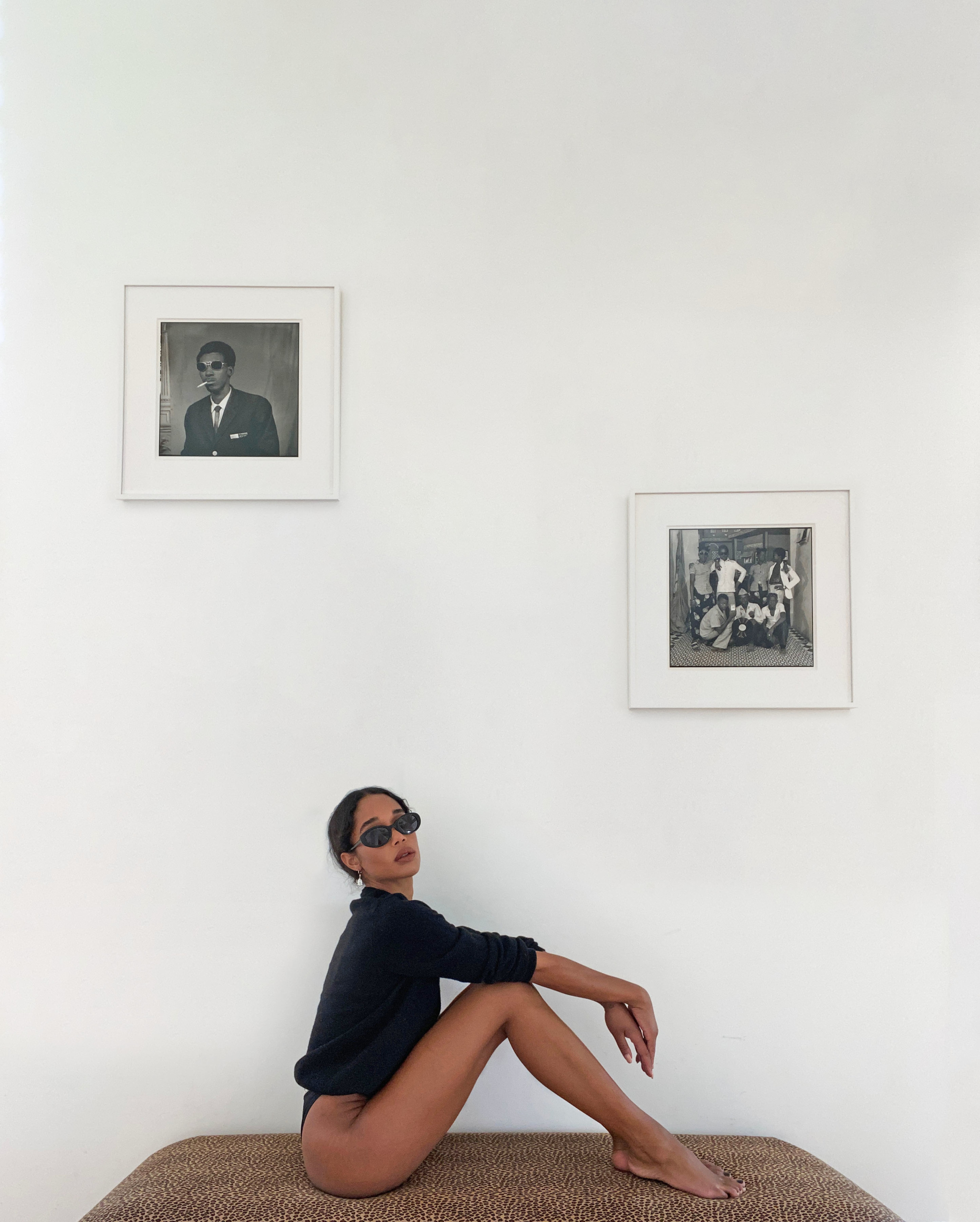 Harrier with her photographs by Sory Sanlé. Harrier wears an Éric Bompard cardigan and glasses by The Row for Oliver Peoples. Portrait by Harrier styled by Danielle Nachmani Goldberg.