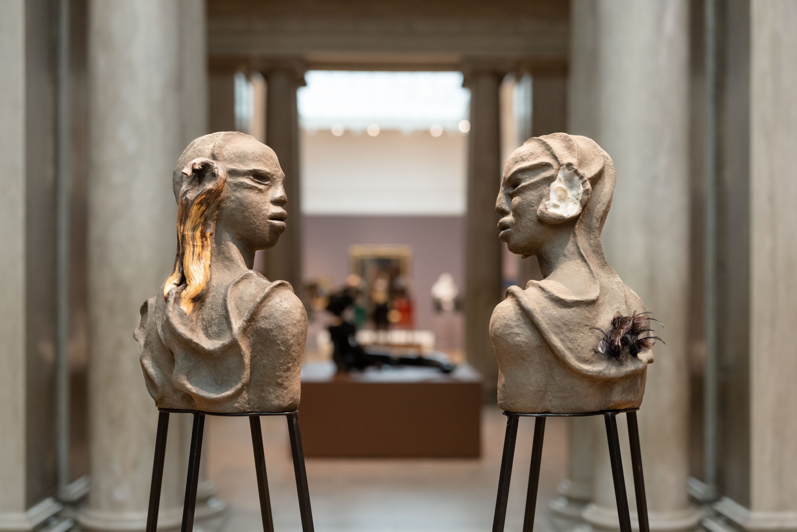 Two bust sculptures facing each other in museum space