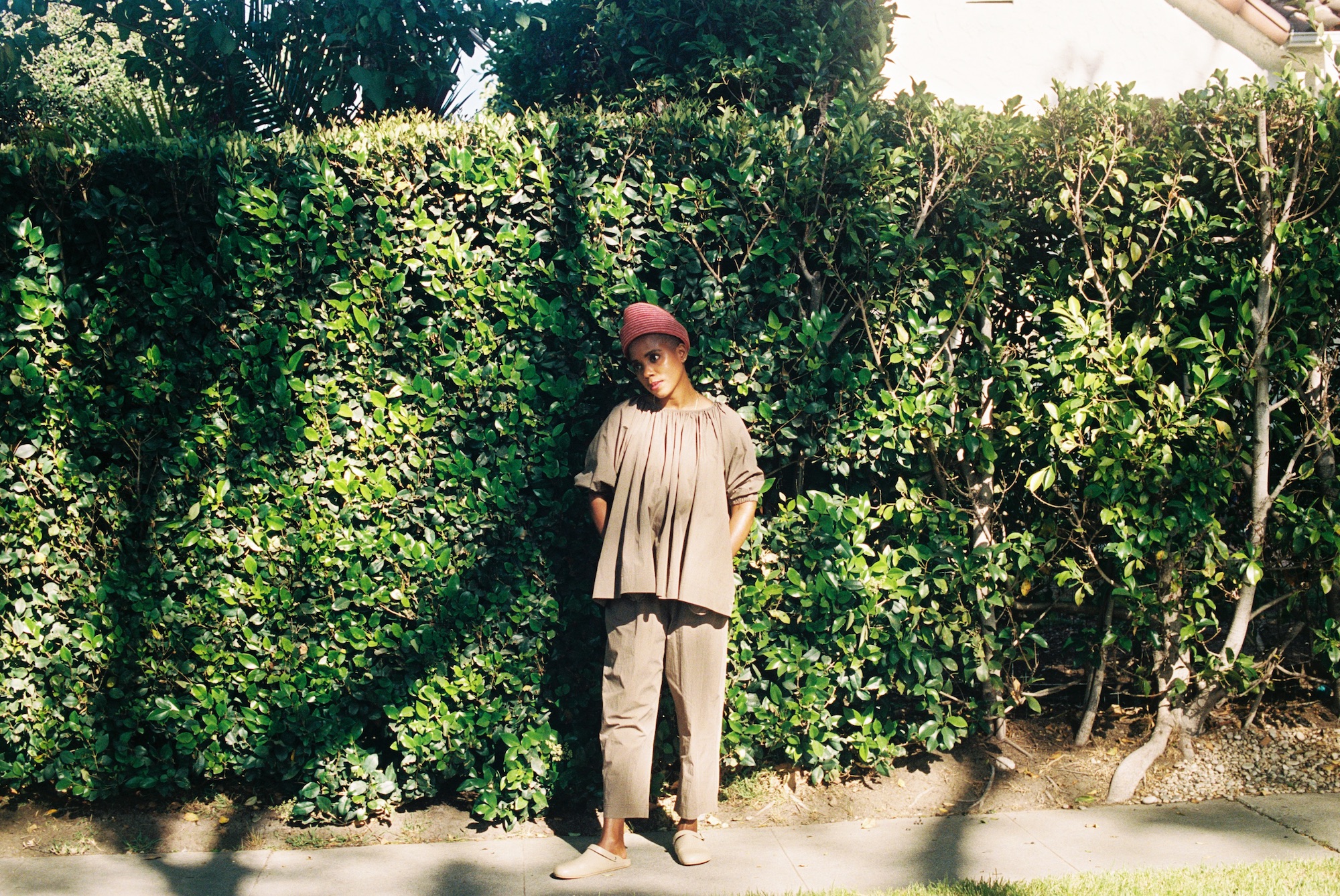 Woman standing in front of hedges janicza bravo