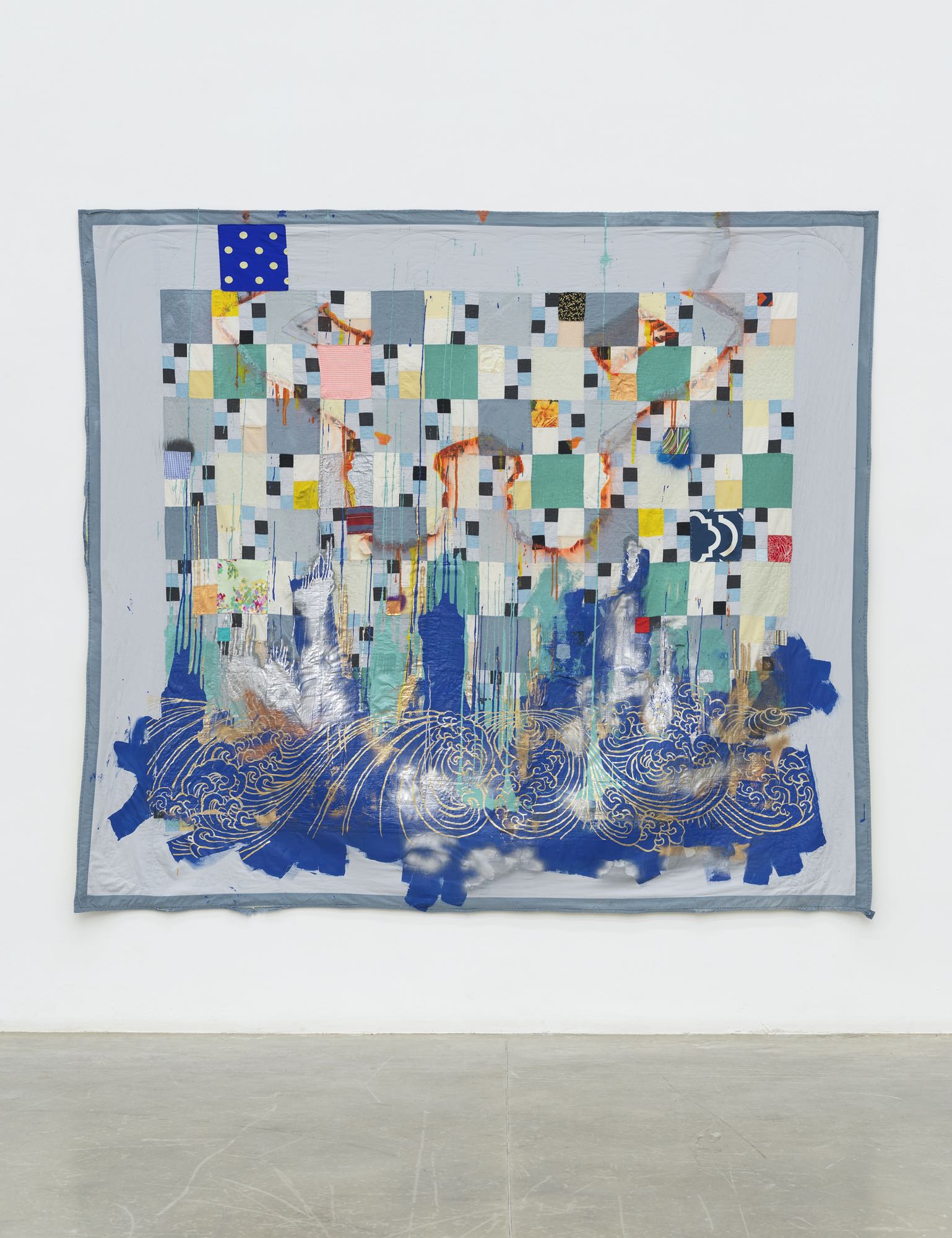 quilt by sanford biggers in gallery space, with square shapes in a pattern, and blue wave on the bottom