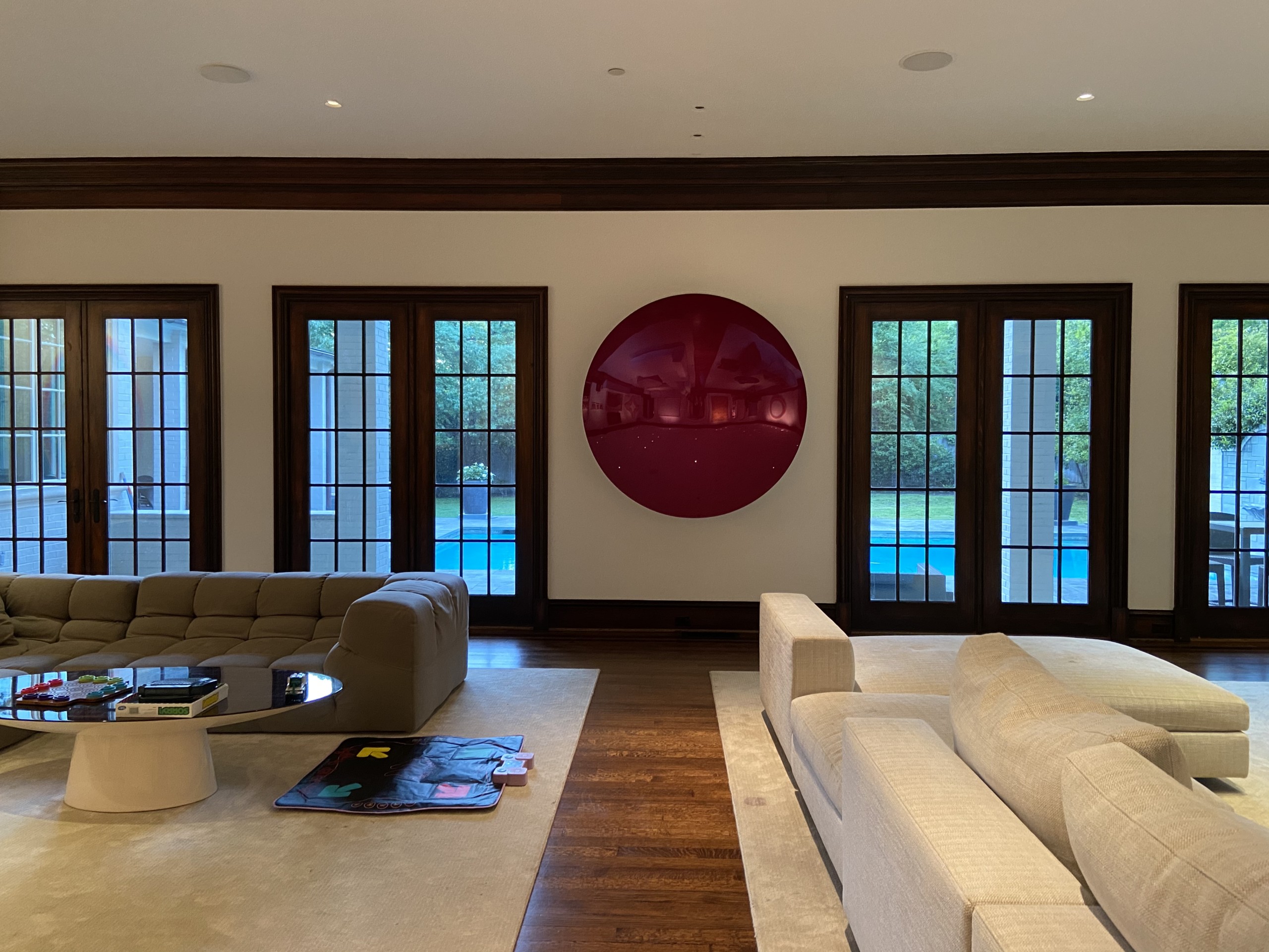 art collector's living room space with large couches and circular art piece hanging in between windows Mark Giambrone