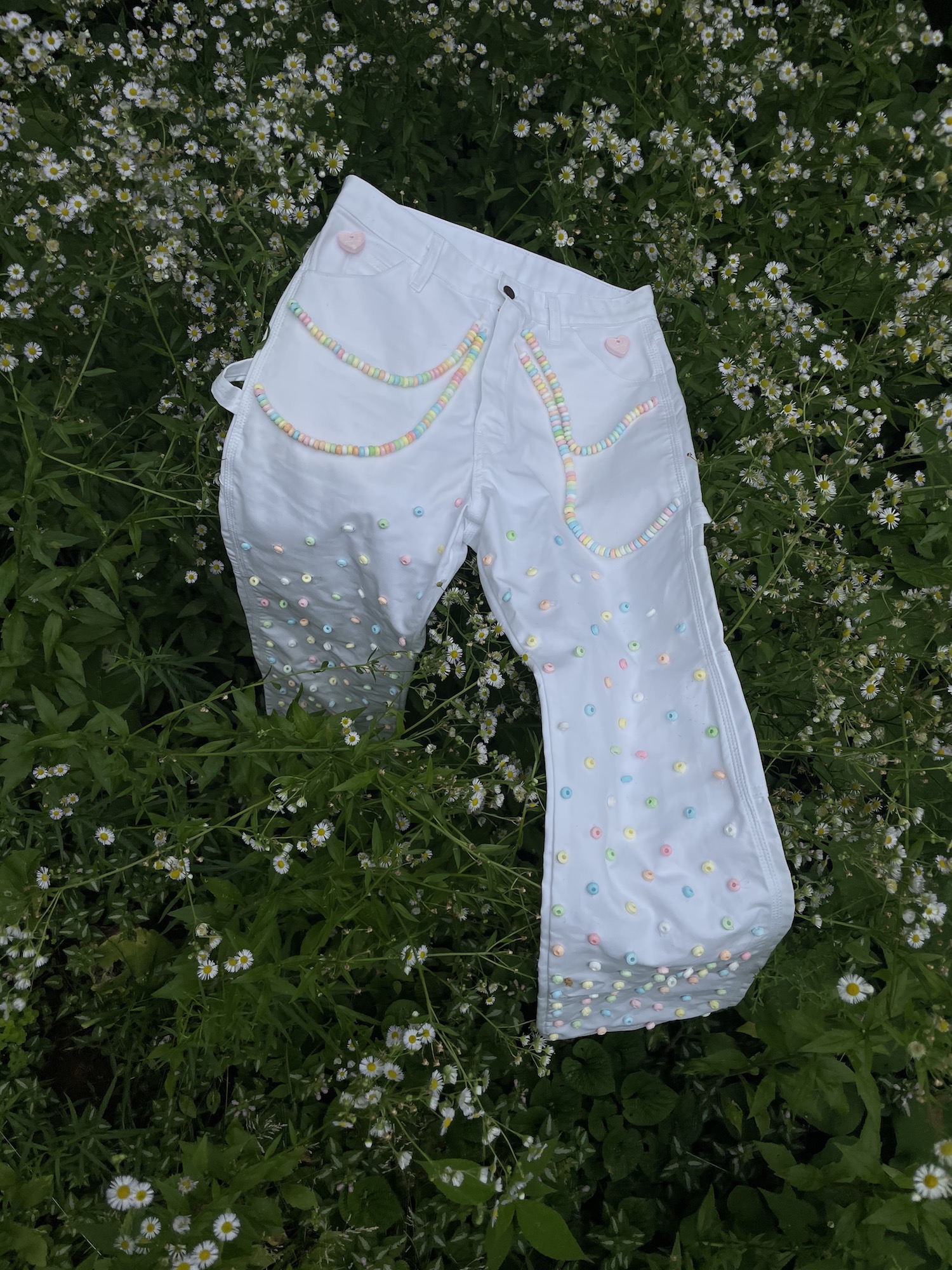 pants with candy necklaces on the pockets resting on flowers in field