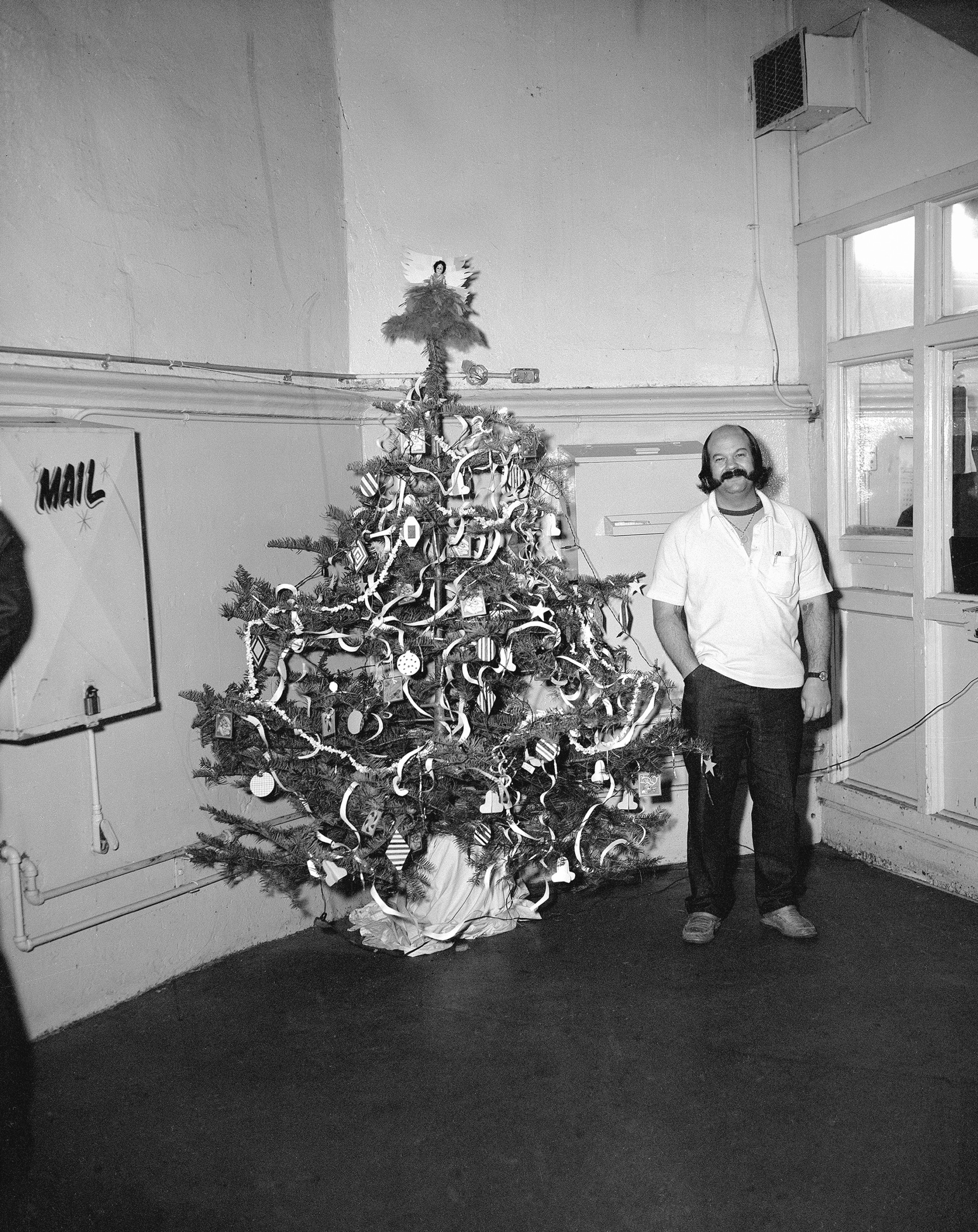 photograph of man in prison standing next to decorated christmas tree