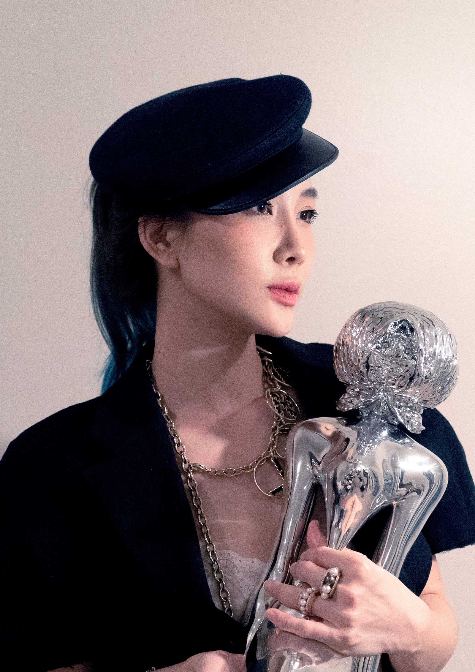 gallerist nalada taechanarong poses with small metal sculpture of skeleton