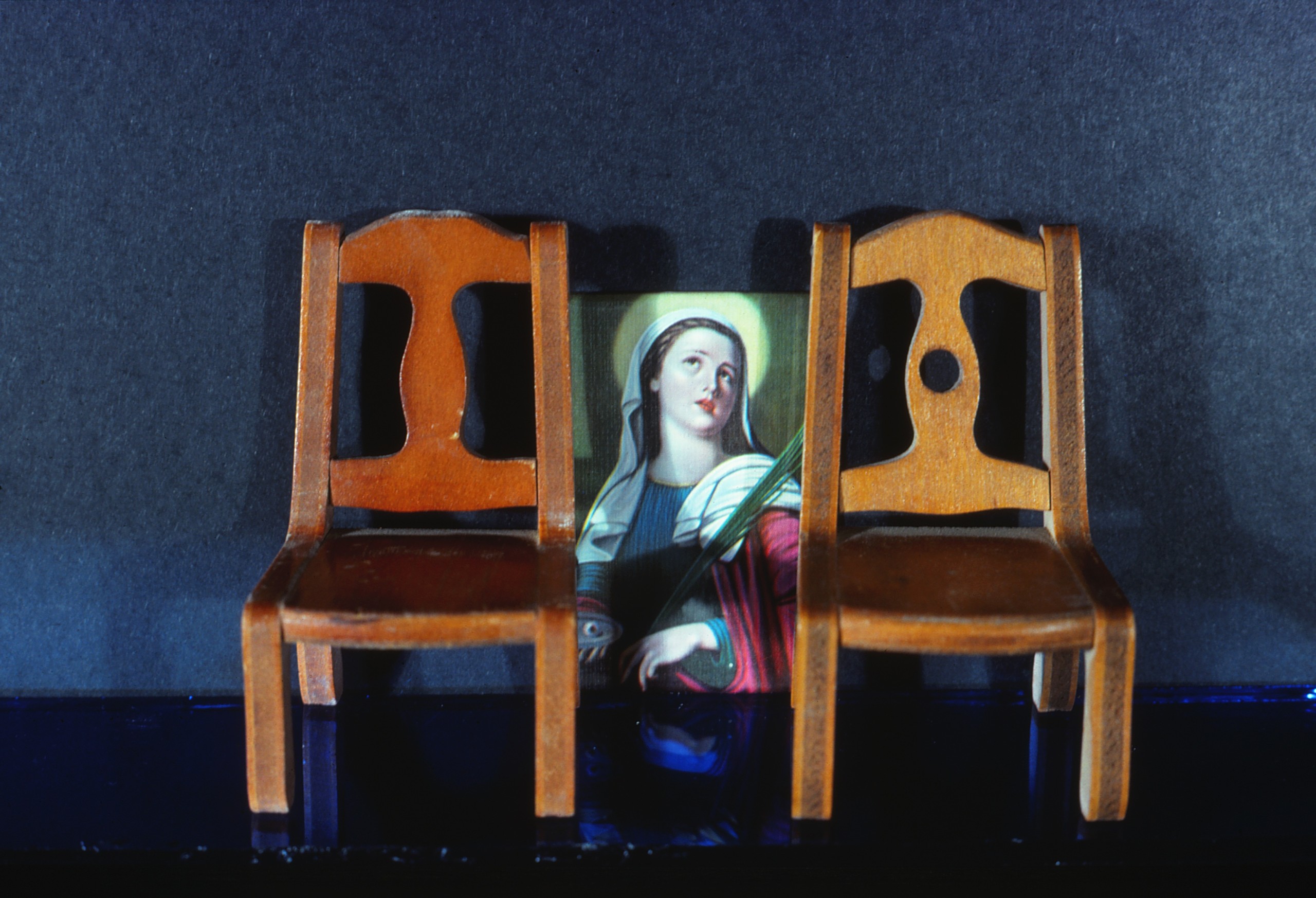 photo of two chairs with painting of the Madonna resting on the floor in between