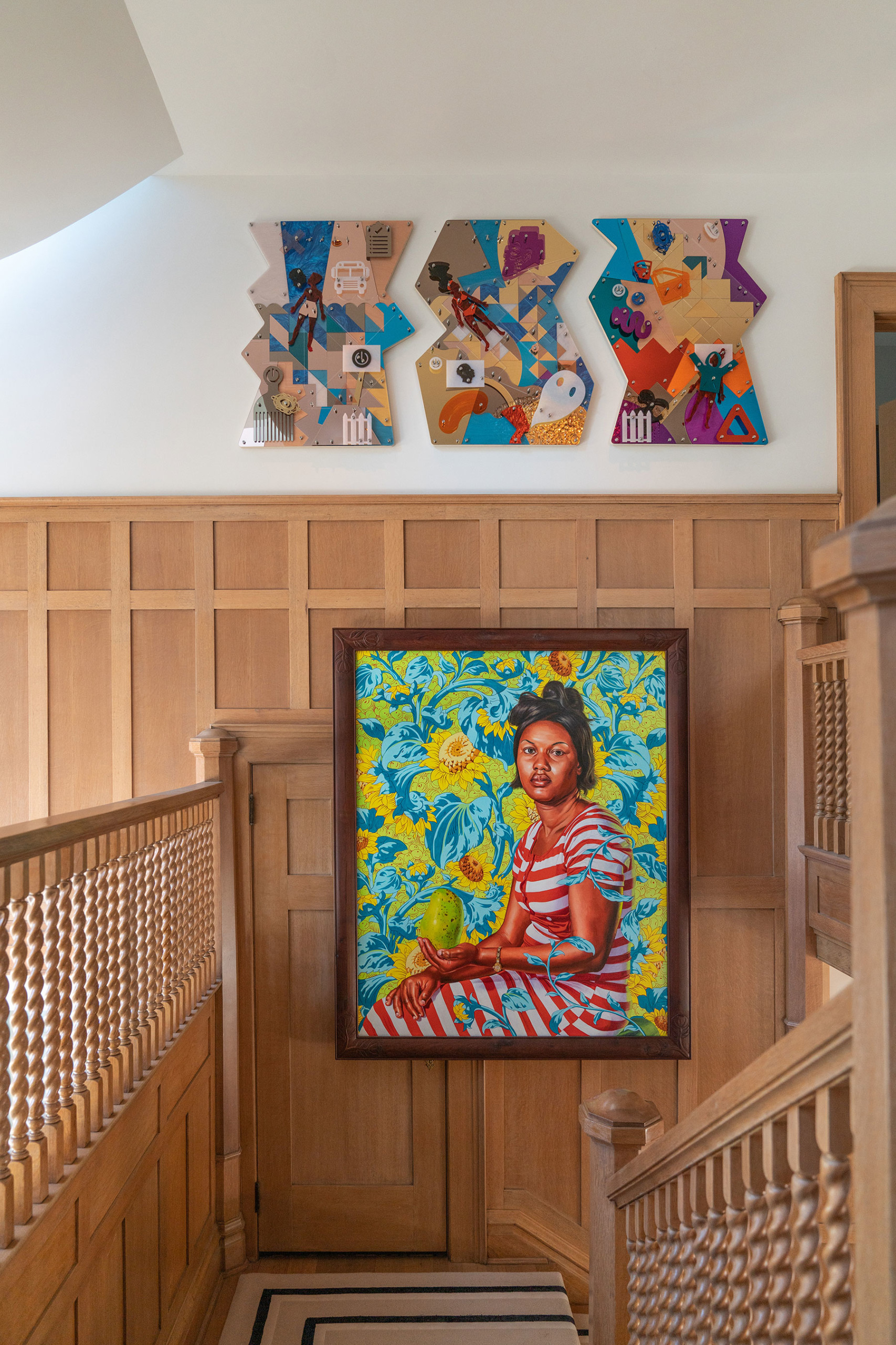 wooden stairwell space in chet callahan home featuring painting by kehinde wiley of portrait with 3 works by damien davis above