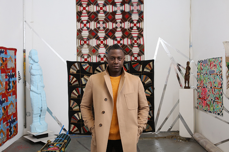 man in front of quilts
