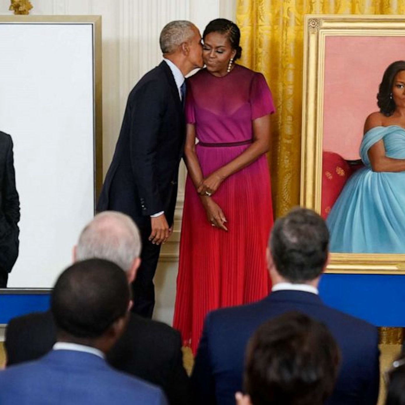 Barack and Michelle Obama in front of their Official White House portraits.