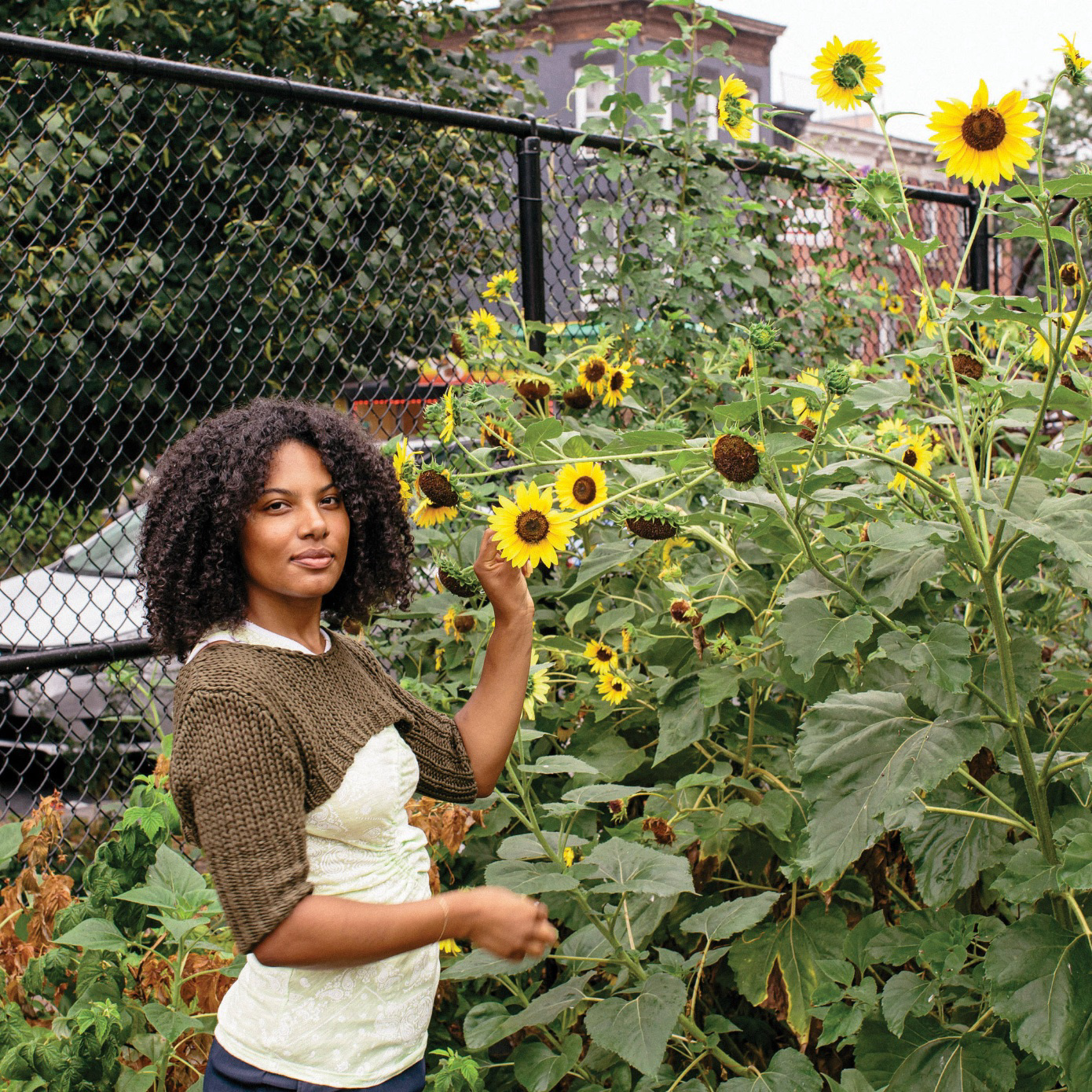 A woman standing in a garden with sunflowers.