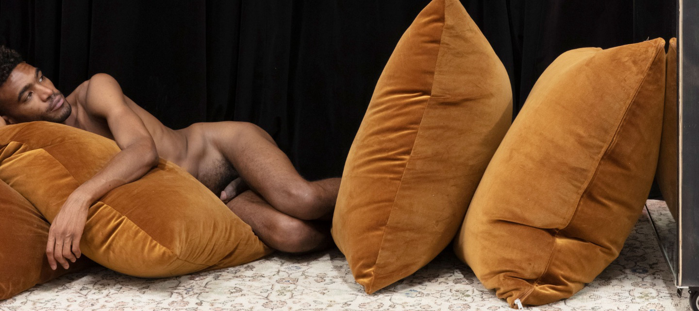 Naked man lays on pillows