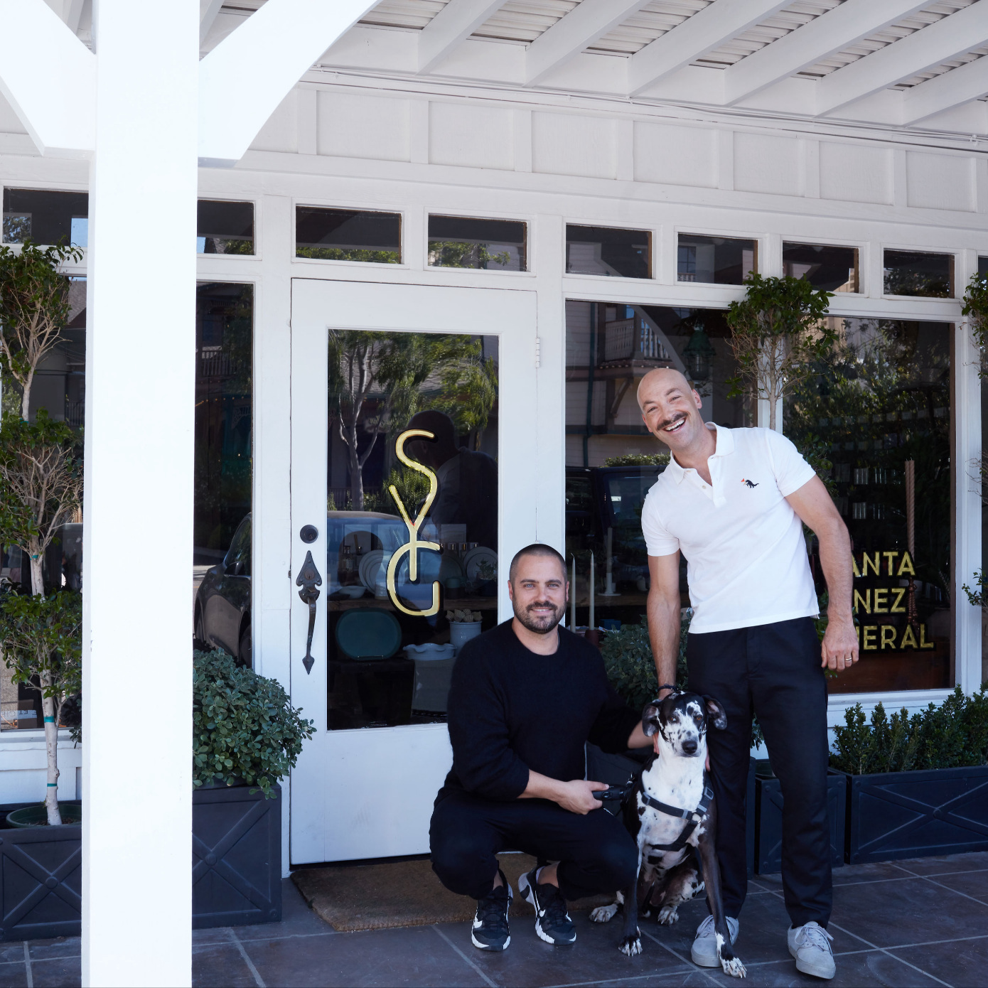 two people with dog in front of store