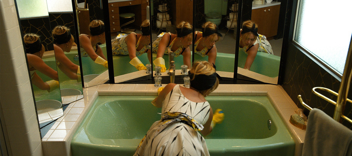 A women cleaning a bath tub and mirrors reflecting her.