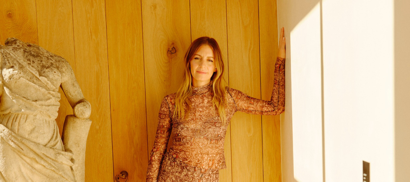 Woman standing next to a sculpture leaning against a wall.