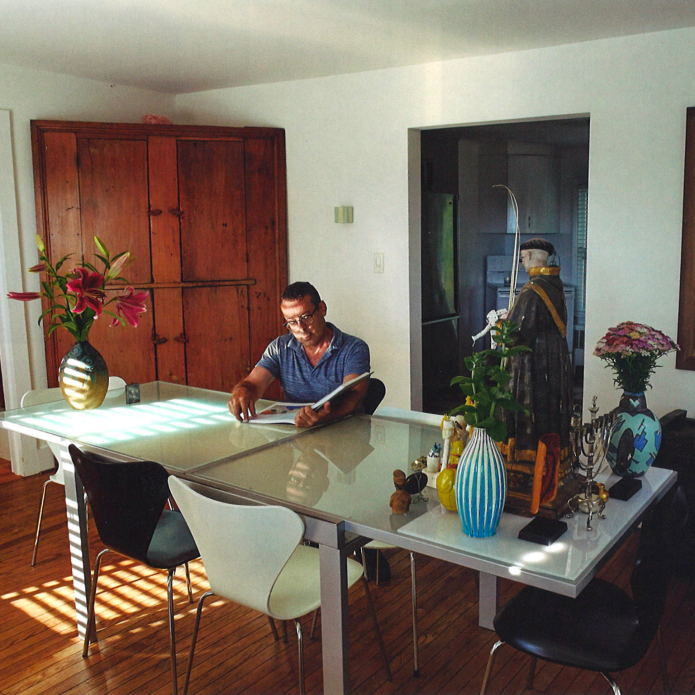 man sits at table surrounded by art