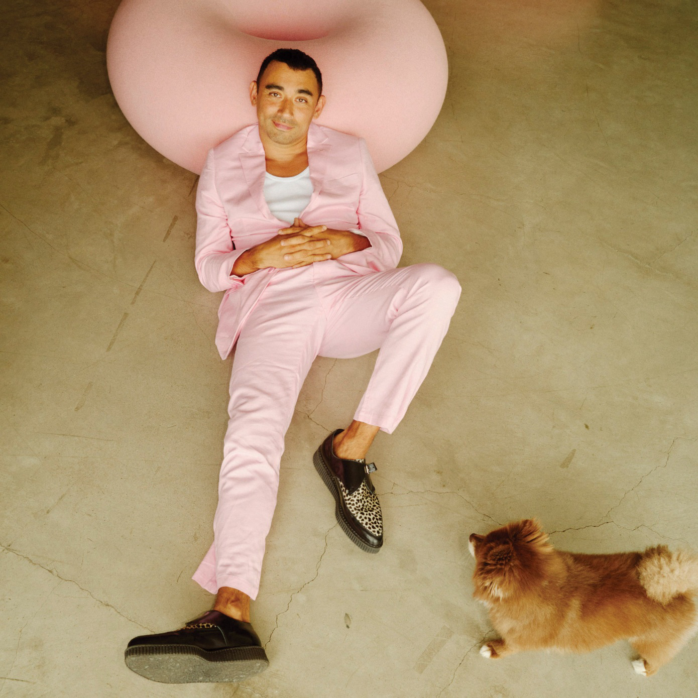 A man lounging on the ground next to a small dog.