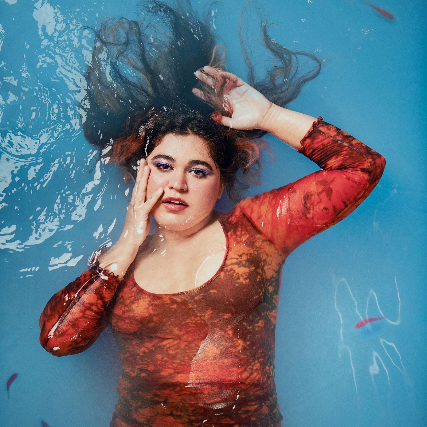 Woman lays in pool with small fish