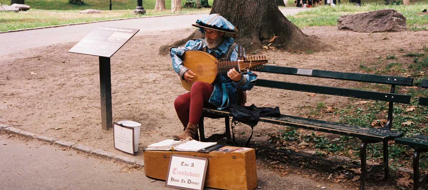 street performer in shakespearean costume performs on bench in central park