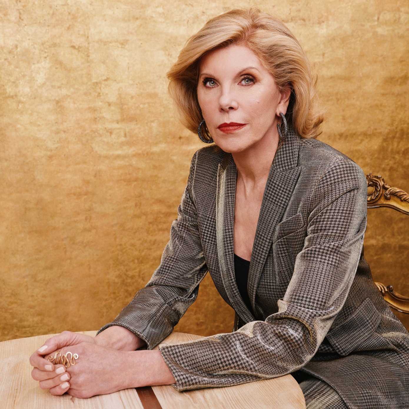 Christine Baranski sitting in a chair at a wooden table.
