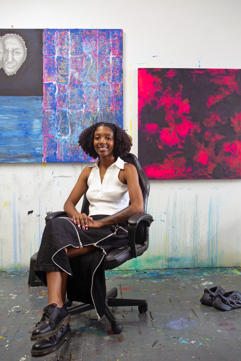 woman in chair with paintings behind