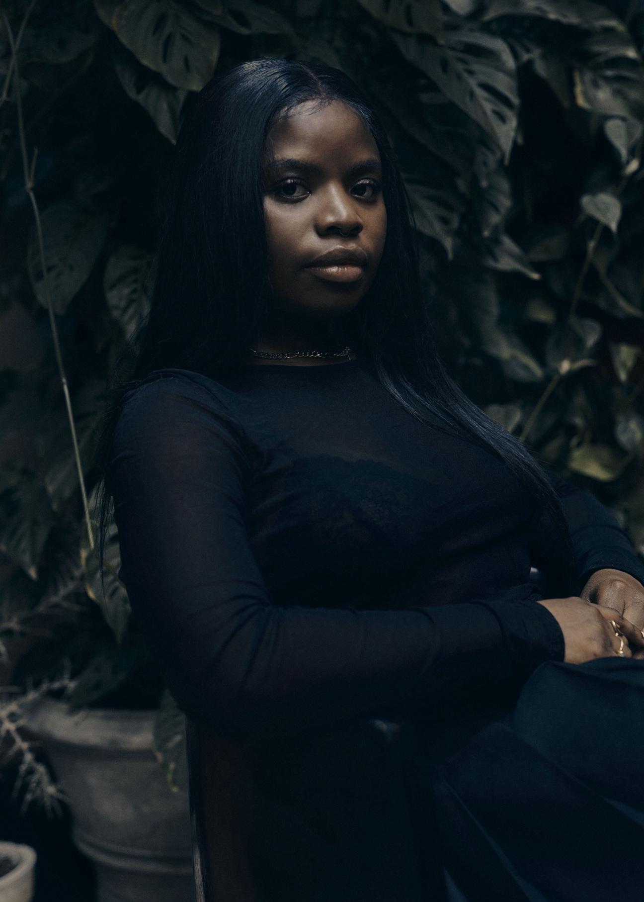 woman vagabon musician sitting against greenery background