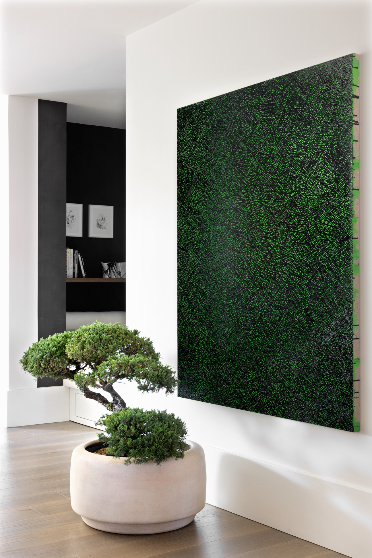 painting hangs in hallway space next to bonsai tree