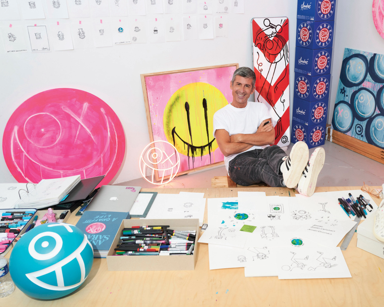 A man sitting in an art studio in front of artwork.