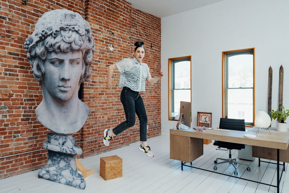 Woman floats in air beside large statue