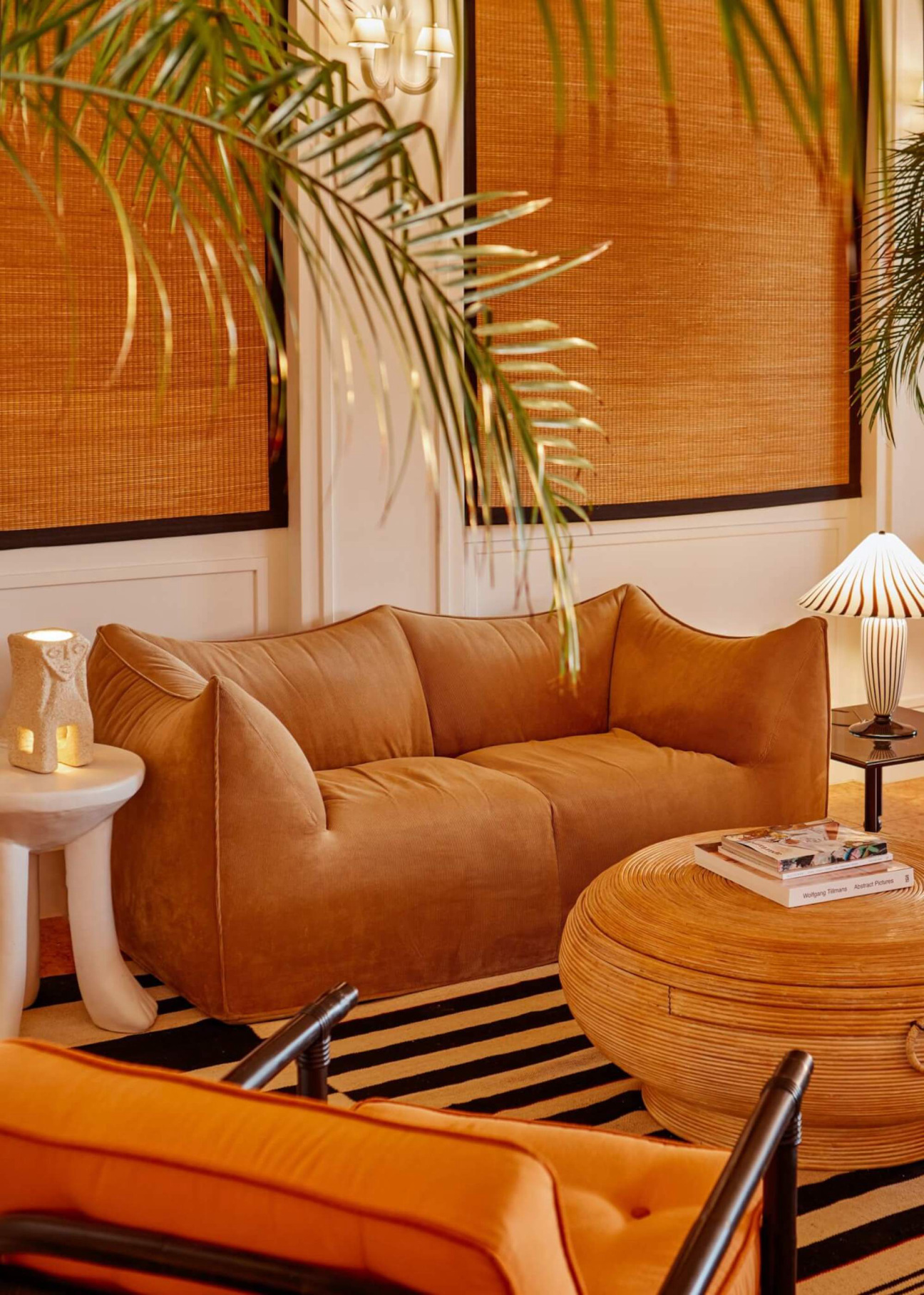 hotel space with geometric couch, palm fronds, and table with vintage magazines