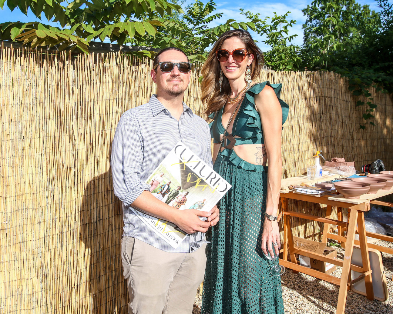 couple poses for photo at gallery party with copy of cultured magazine