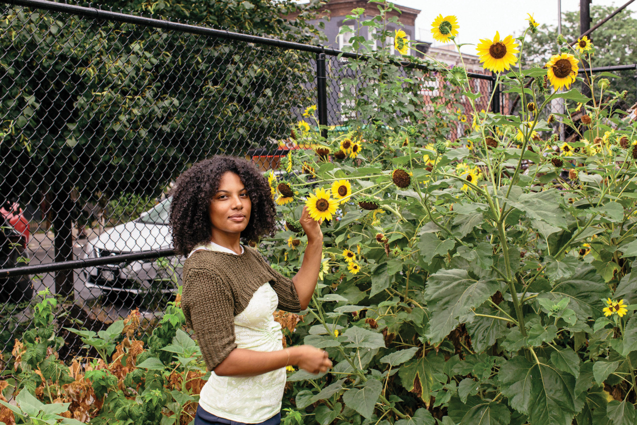 A woman standing in a garden with sunflowers.