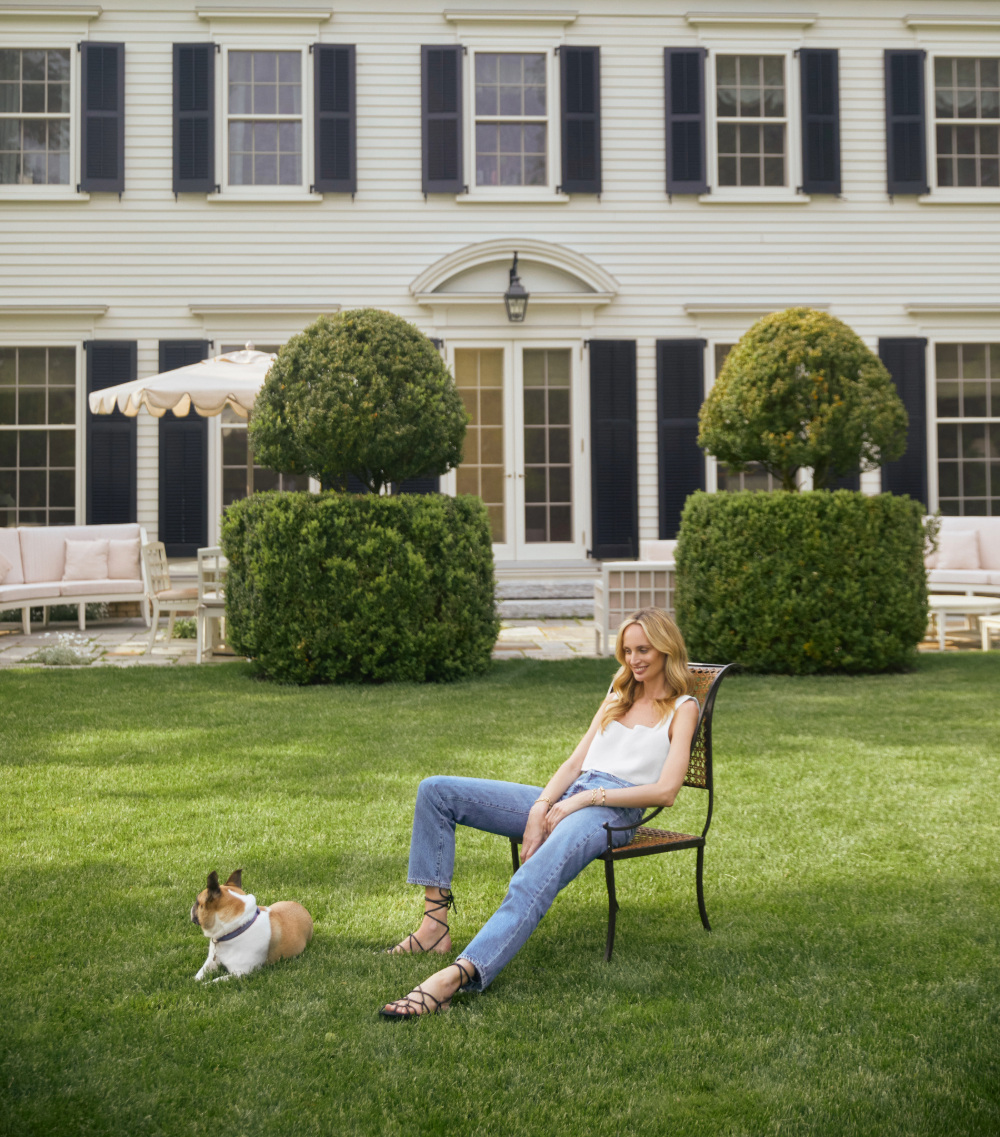 White woman sitting on the lawn in front of a house.